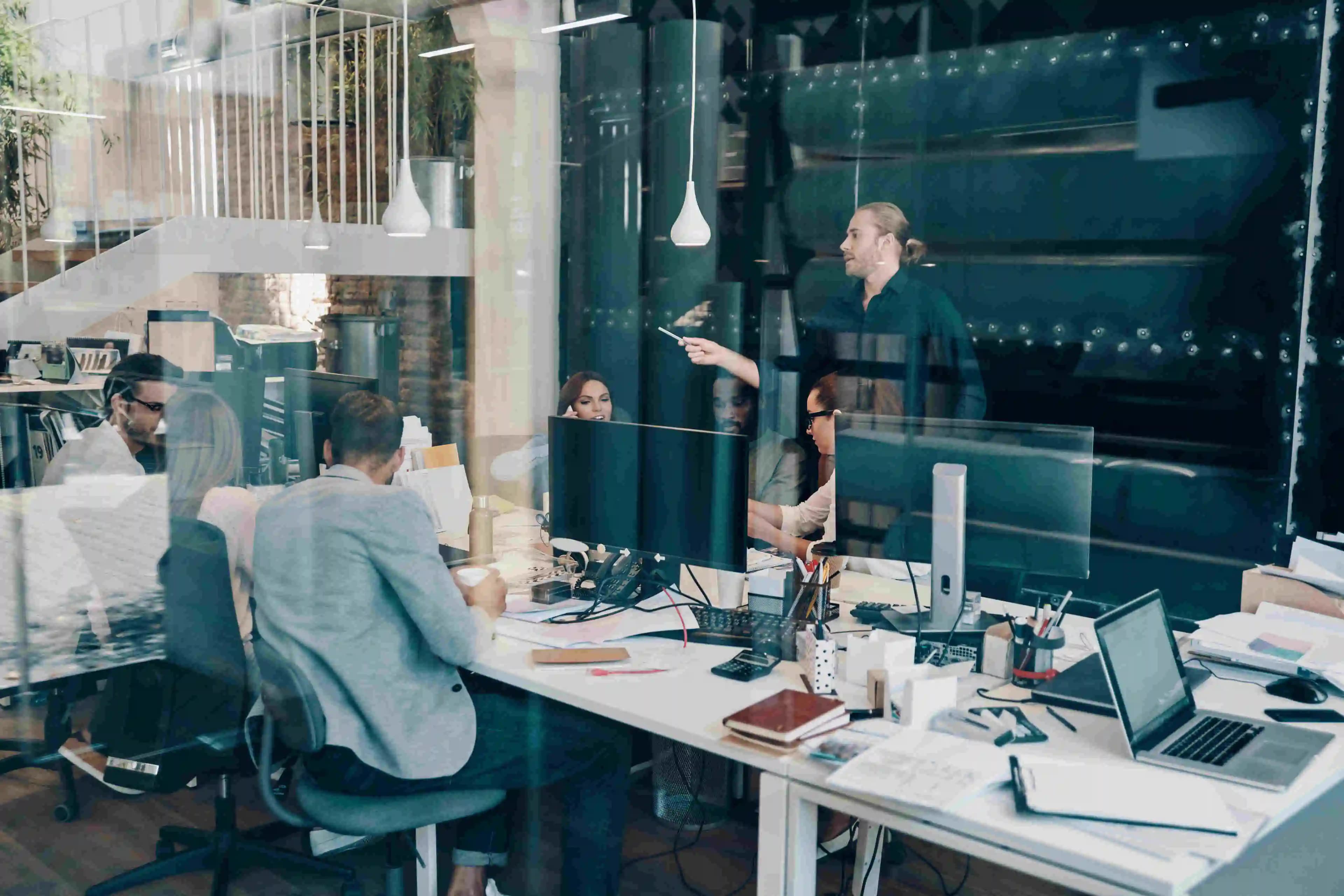 IT-Spezialisten, die in ihrer Arbeit vertieft sind, umgeben von Technologie in einem modernen Büro, wo Innovation auf Effizienz trifft.